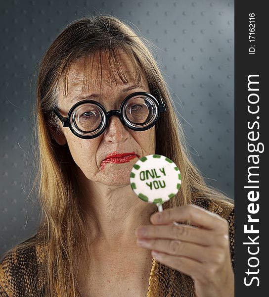 Mid Adult Women with Granny Glasses holding in her Hand Gift/Present Lolly. Mid Adult Women with Granny Glasses holding in her Hand Gift/Present Lolly