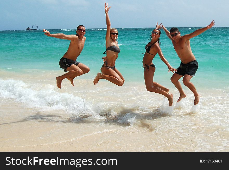 Four people are jumping in the ocean water. Four people are jumping in the ocean water