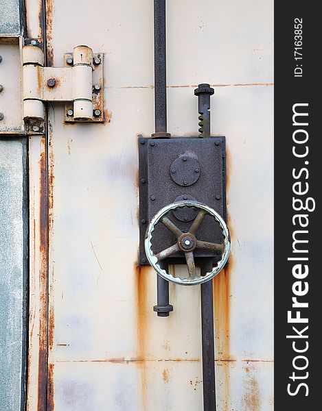 Rusty iron lock on the harbor warehouse door; focus on the wheel and lock's body. Rusty iron lock on the harbor warehouse door; focus on the wheel and lock's body