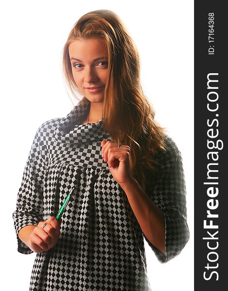 Blonde girl in a checkered dress with pen on the white background with the dismissed hair looks in the camera