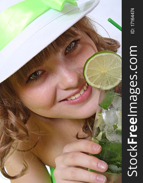 The girl in a hat holds an alcoholic drink with a citrus. The girl in a hat holds an alcoholic drink with a citrus