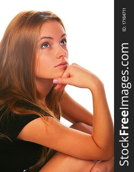 Blonde girl in the black dress, sitting on a white background and looks into the camera. Blonde girl in the black dress, sitting on a white background and looks into the camera