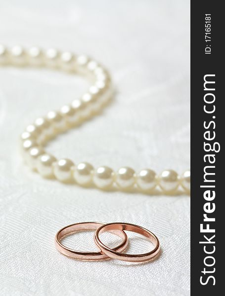 Wedding rings and pearl necklace on lace background