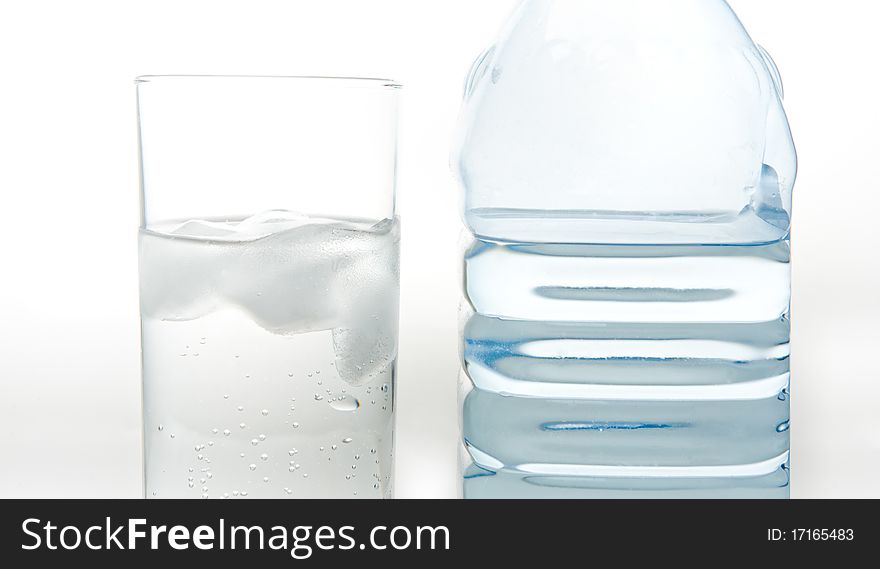 A bottle of fresh mineral water and a glass which is poured the same water on a white background