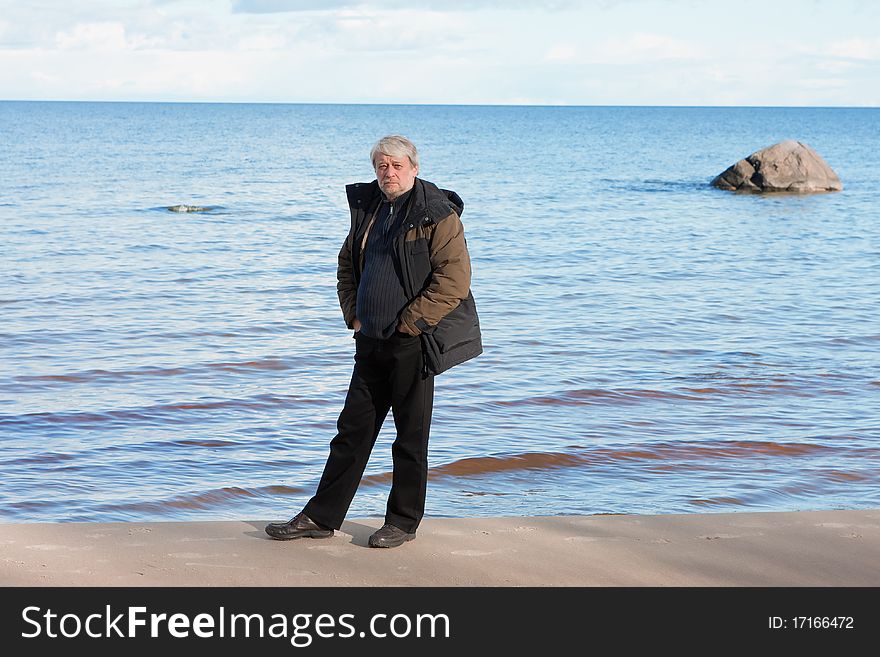 Mature man with grey hair relaxing at the Baltic sea in autumn day. Mature man with grey hair relaxing at the Baltic sea in autumn day.