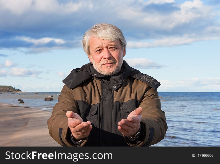 Mature poor man with grey hair at the Baltic sea asks for help in autumn day. Mature poor man with grey hair at the Baltic sea asks for help in autumn day.
