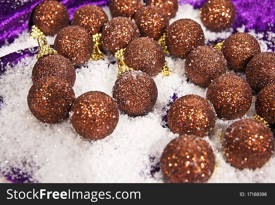 Decorations christmas brown balls on the snow and on violet background. Decorations christmas brown balls on the snow and on violet background.