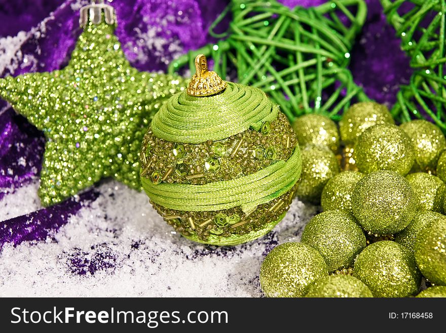 Decorative christmas green balls with star on the snow and on violet background. Decorative christmas green balls with star on the snow and on violet background.