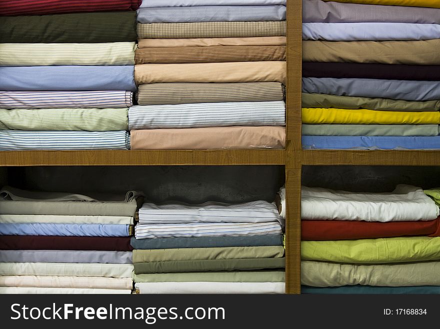 Shelves stacked with different shirt fabrics in Tailors