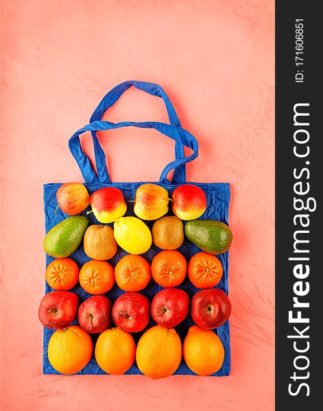 Eco-friendly cotton bag in blue color against a peach color background. Zero waste concept, plastic-free, eco-friendly shopping with fruits and vegetables, , image with copy space. Eco-friendly cotton bag in blue color against a peach color background. Zero waste concept, plastic-free, eco-friendly shopping with fruits and vegetables, , image with copy space
