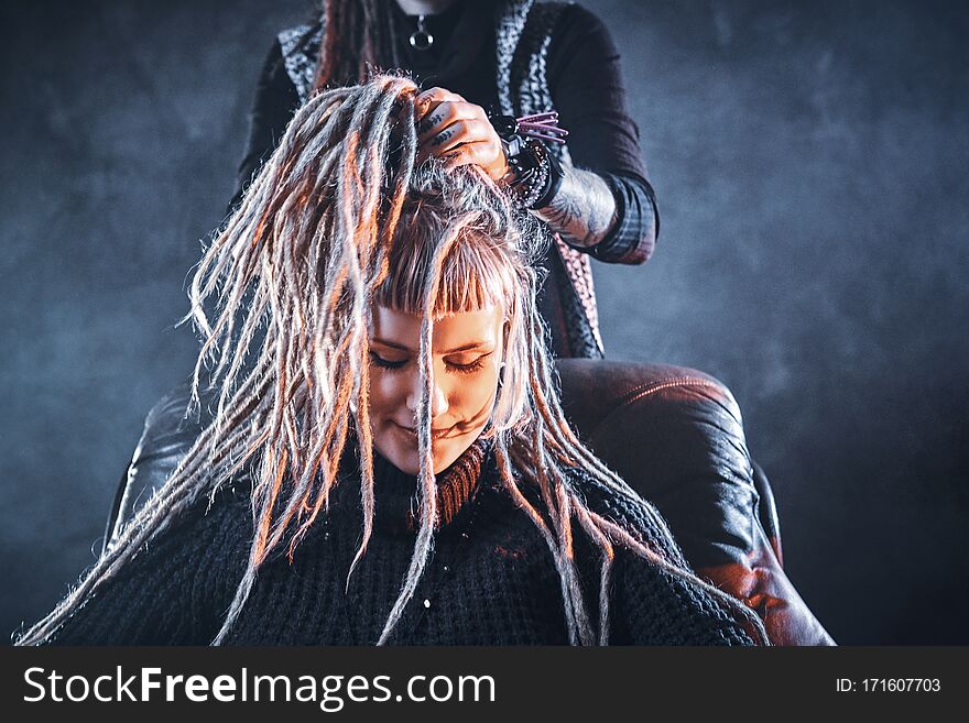 Young pensive women got new freaky hairstyle from dreadlocks master. Young pensive women got new freaky hairstyle from dreadlocks master.