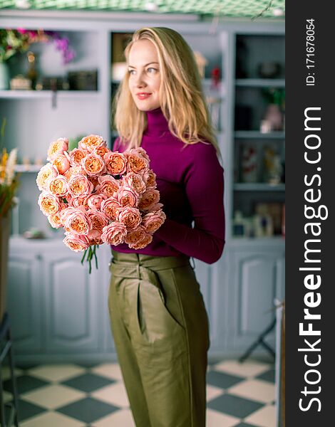 Female florist creating beautiful bouquet in flower shop, close up