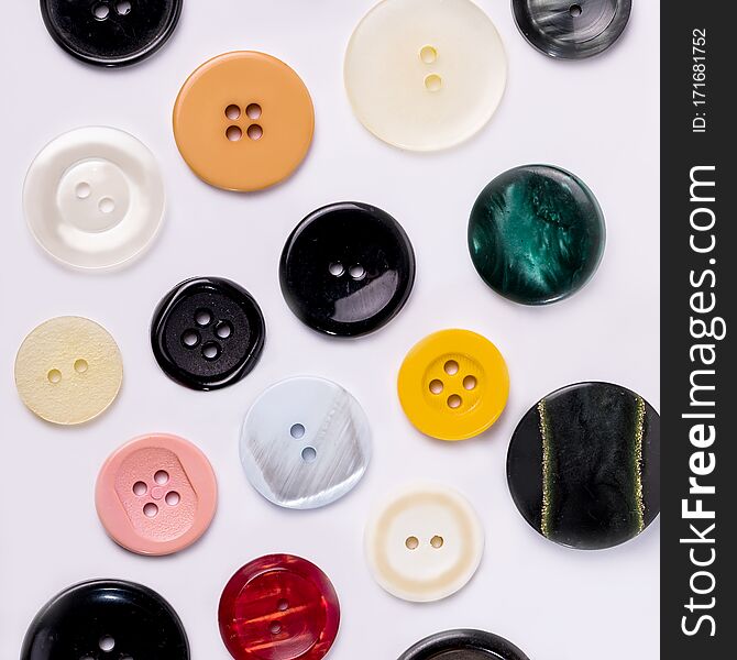 A collection of different spare clothing buttons. Different buttons on a white table for sewing clothes.