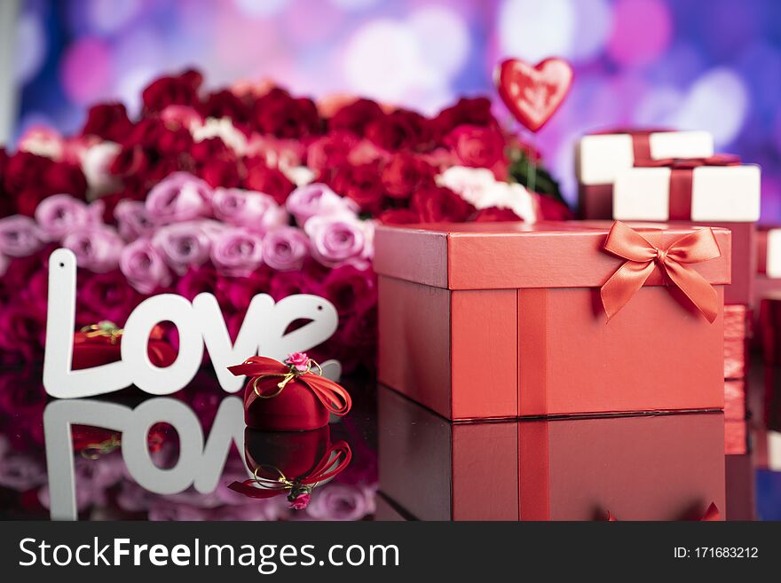 Gifts in boxes, red hearts and big bouquet of natural roses on blue bokeh background. Gifts in boxes, red hearts and big bouquet of natural roses on blue bokeh background.