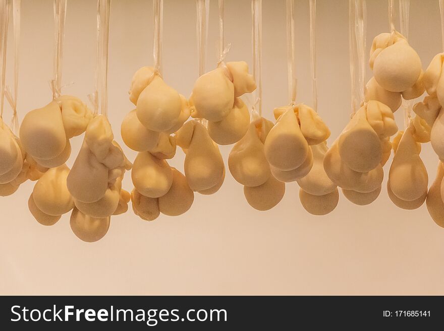 A group of little mozzarellas pouches dry hanging in row on ceiling become mature. Delicious traditional dairy italian premium food. A group of little mozzarellas pouches dry hanging in row on ceiling become mature. Delicious traditional dairy italian premium food