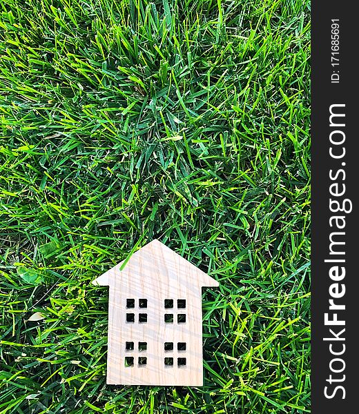 Miniature wooden house on green grass. Real estate concept. Modern housing. Eco-friendly and energy efficient house. Buying a home