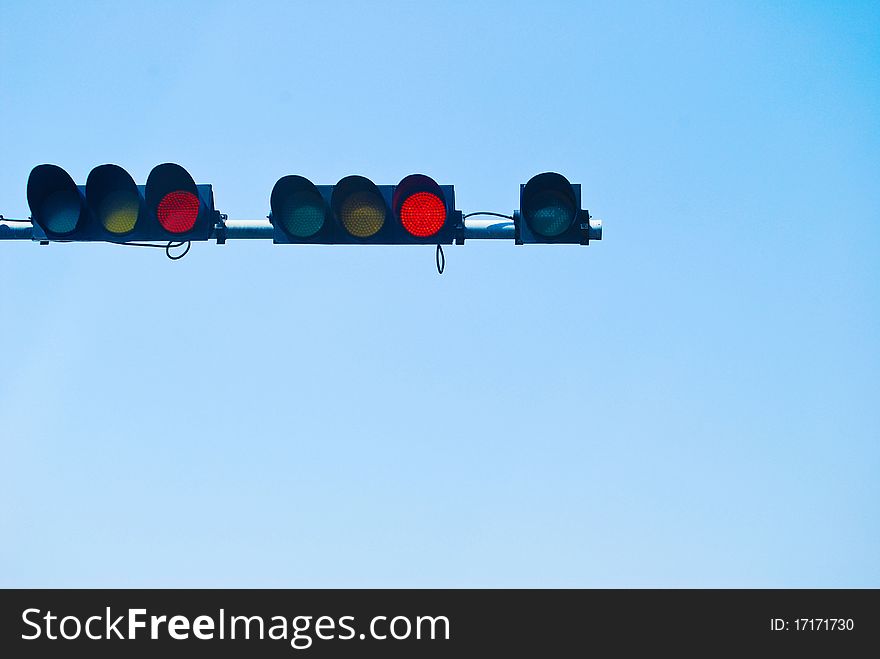 Red color on the traffic light on the blue sky background