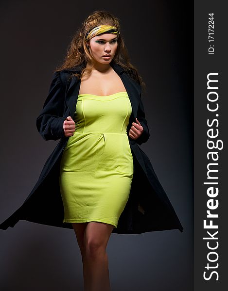 Young sensual woman in yellow dress and black jacket isolated on black