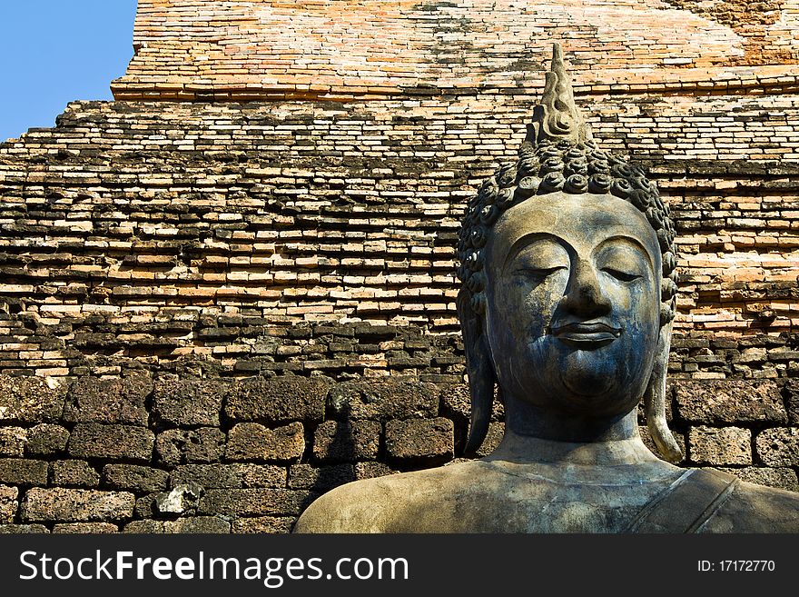 Ancient Buddha statue with brick wall