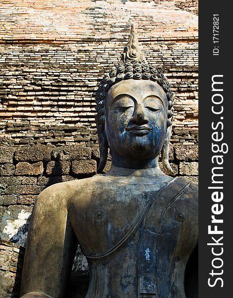 Ancient Buddha statue with brick wall