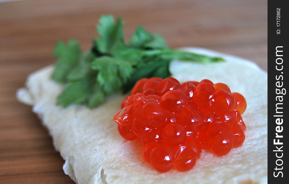 Red caviar on pancake with parsley