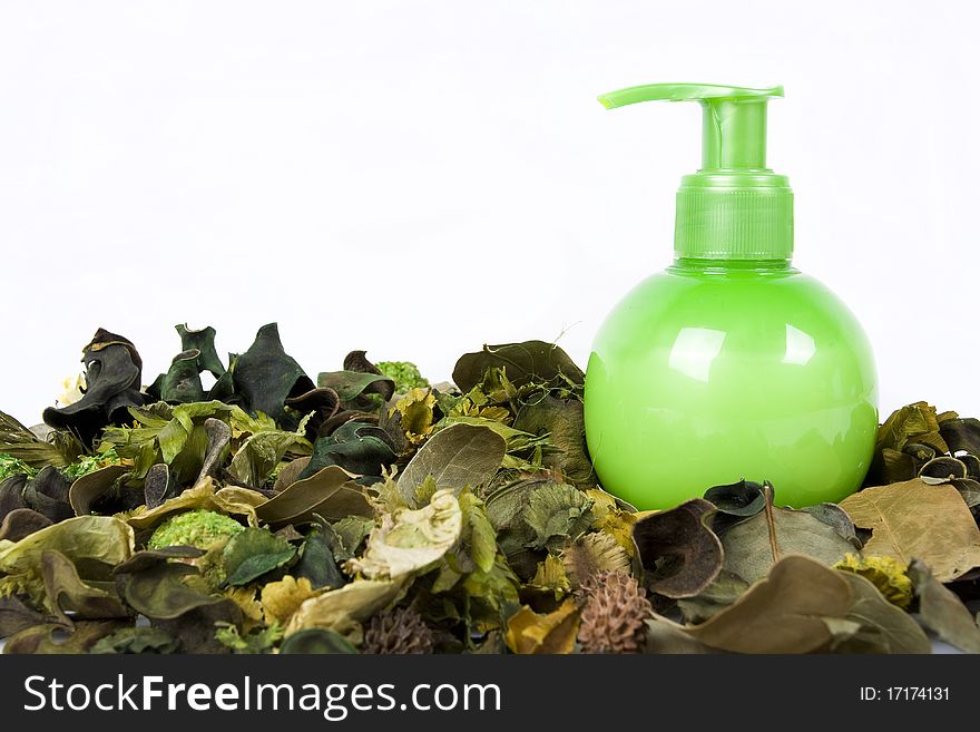 Green cream bottle with some dry leaves isolated on white background