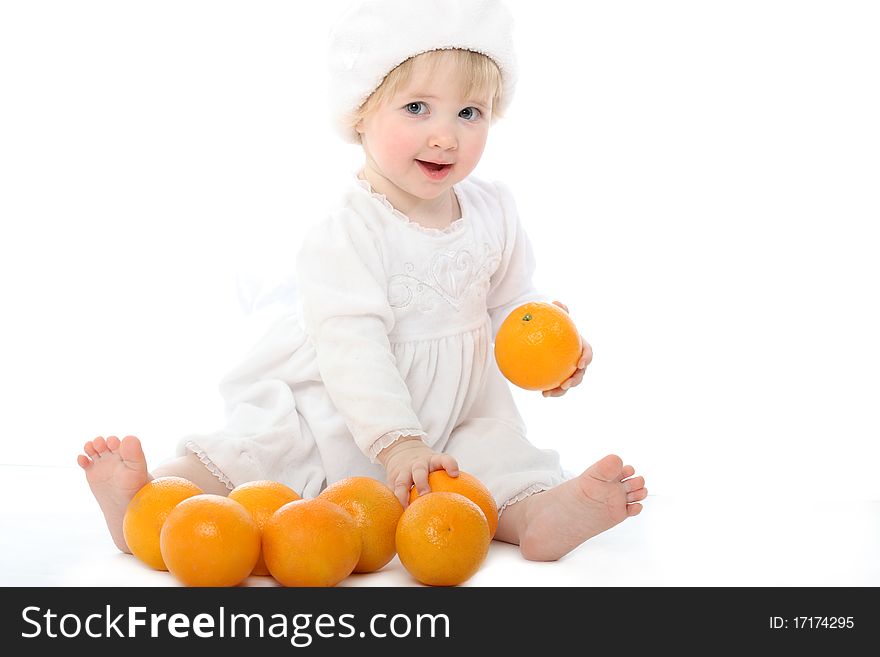 Smiling barefooted baby with oranges