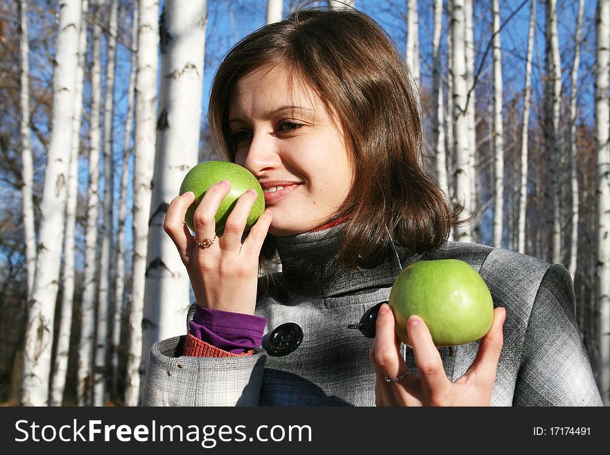The young girl in a checkered coat with two green apples. The young girl in a checkered coat with two green apples