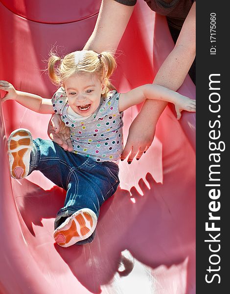Happy smiling blonde toddler girl on playground slide. Happy smiling blonde toddler girl on playground slide