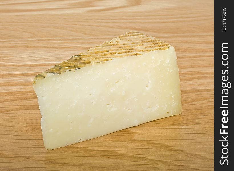 A slice of hard cheese on a wooden surface
