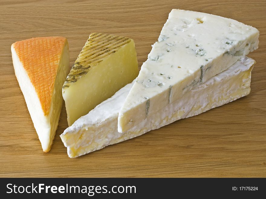 Four continental cheeses on a wood surface