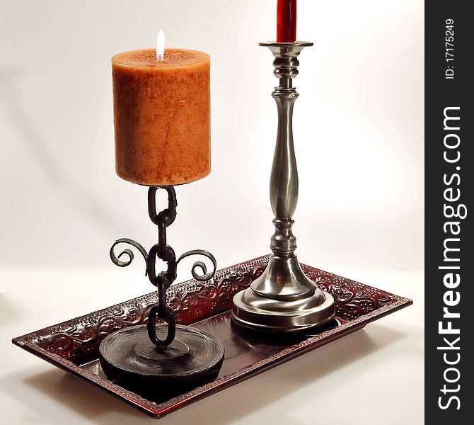 Two candles in their candle holders sitting in a bronze platter. Two candles in their candle holders sitting in a bronze platter.