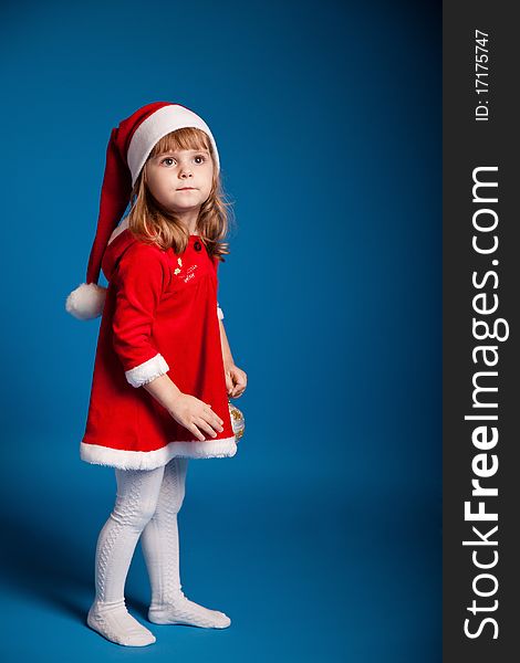 Sweet little girl dressed in santa costume on dark blue background