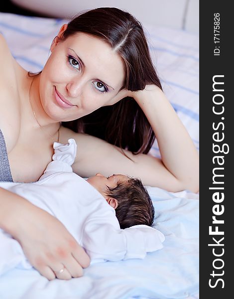 Beautiful young mum and newborn son lying on a bed