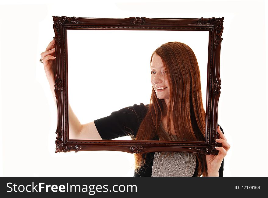 An young woman with long red hair holding a picture frame, in a black dress, with empty copy space in the frame, on white background. An young woman with long red hair holding a picture frame, in a black dress, with empty copy space in the frame, on white background.
