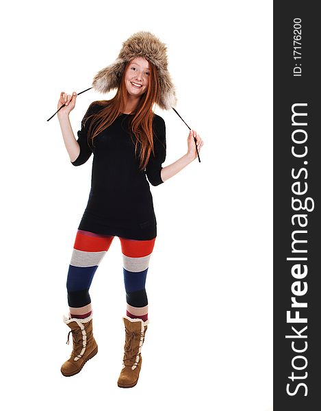 A pretty woman with long red hair in colorful tights, a black sweater and a fur hat and brown boots smiling for a portrait for white background. A pretty woman with long red hair in colorful tights, a black sweater and a fur hat and brown boots smiling for a portrait for white background.