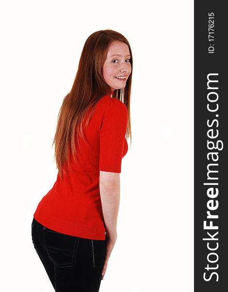 A young cute woman standing from the back, looking over her shoulder in a red sweater and jeans, with long red hair, for white background. A young cute woman standing from the back, looking over her shoulder in a red sweater and jeans, with long red hair, for white background.