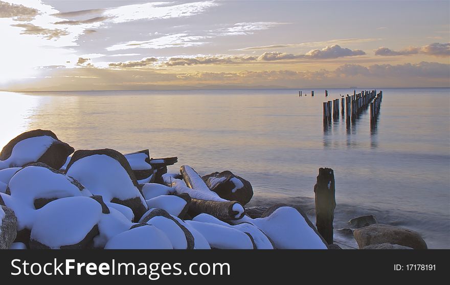 Sunset on a snowy winter day overlooking an old pier. Sunset on a snowy winter day overlooking an old pier.