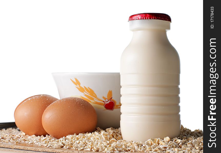 A bottle of milk, eggs and oatmeal on the wooden surface. A bottle of milk, eggs and oatmeal on the wooden surface