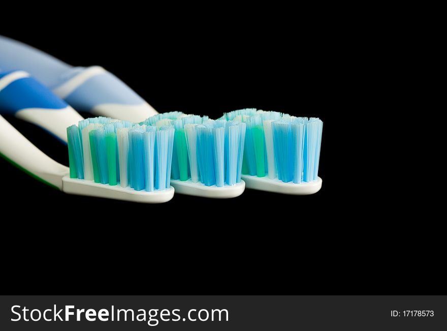 Three toothbrushes isolated on a black background.