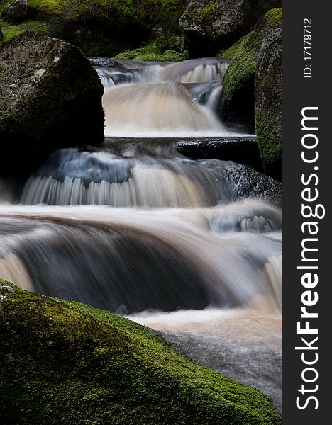 Motion blurred wild river flowing over the mossy stones