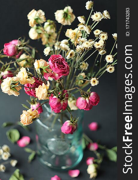 dry pink beige roses in a glass vase on a dark background blurred background. dry pink beige roses in a glass vase on a dark background blurred background