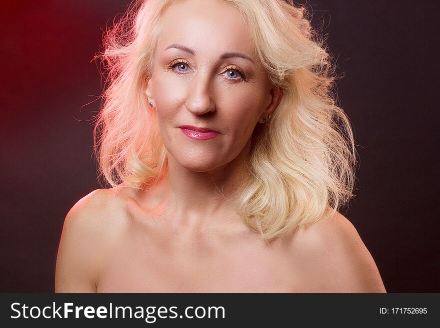 Portrait old woman in colorful bright lights. red and gold color, dark maroon background