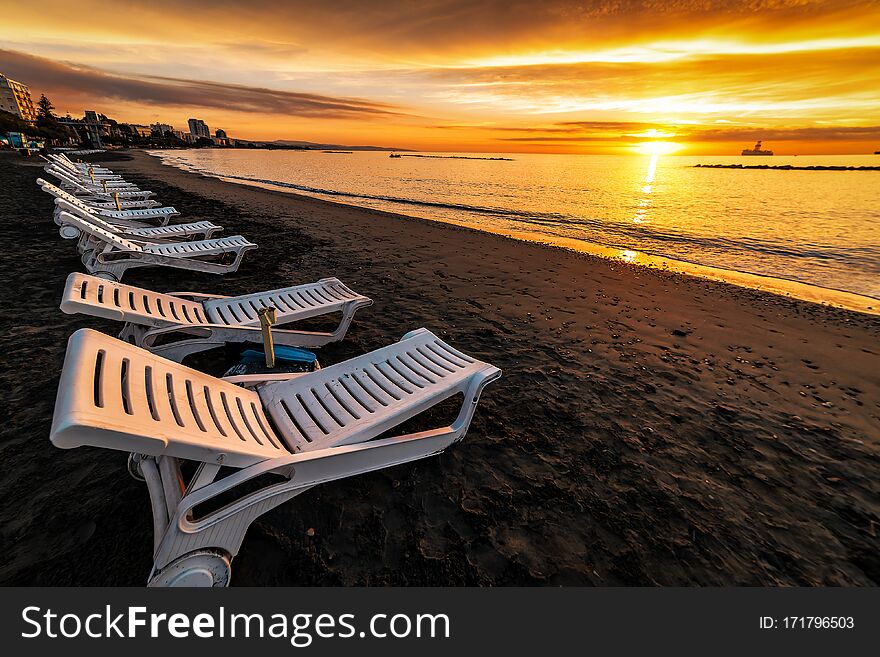 Row sun beds on beautiful sunrise over the sea