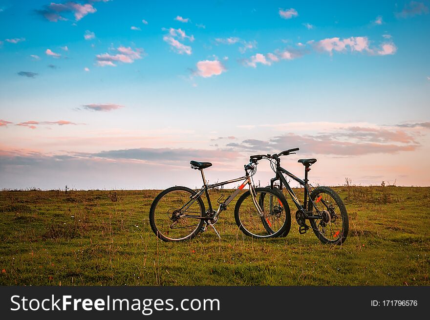 Two bicycles on green grass at beautiful sunset. Two bicycles on green grass at beautiful sunset