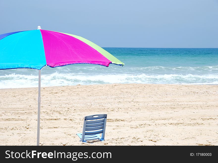Colored beach umbrella and empty chair on sea coast. Colored beach umbrella and empty chair on sea coast.