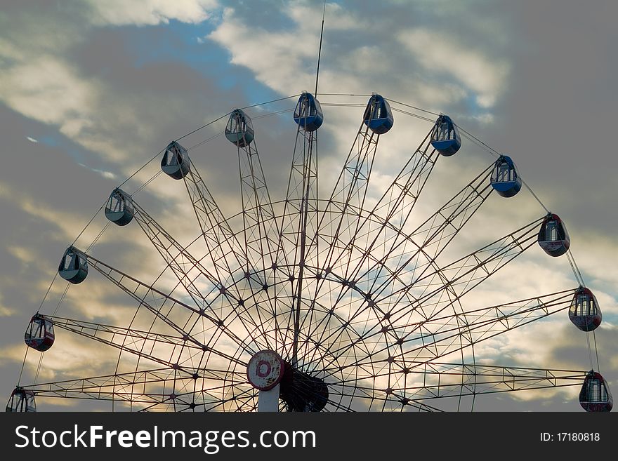 A set of ferris wheel is in the evening mist background.