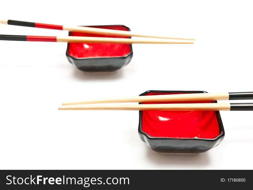 Black and red chopsticks and plates isolated on white background