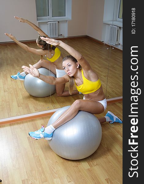 Girl in shorts do exercise on big ball in gym