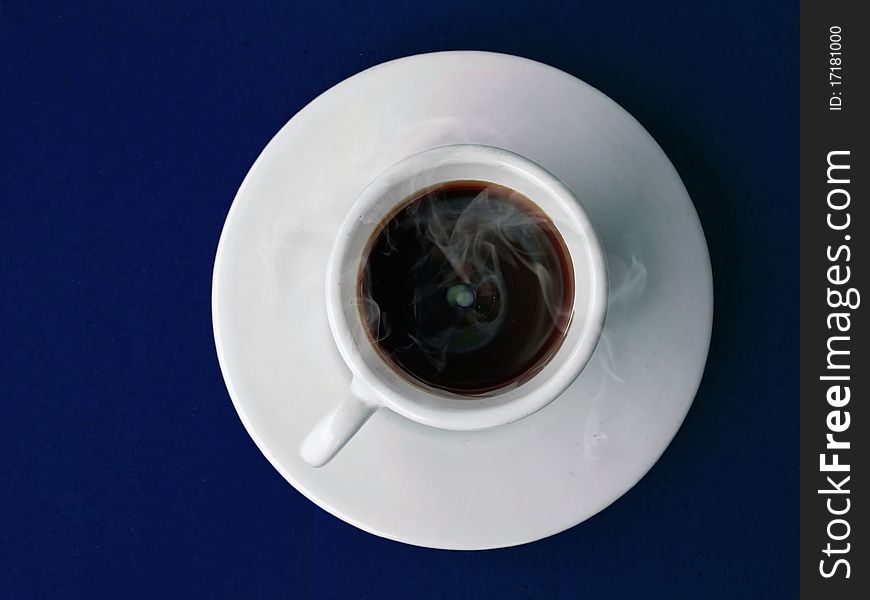 White ceramic cup of hot coffee on dark blue table